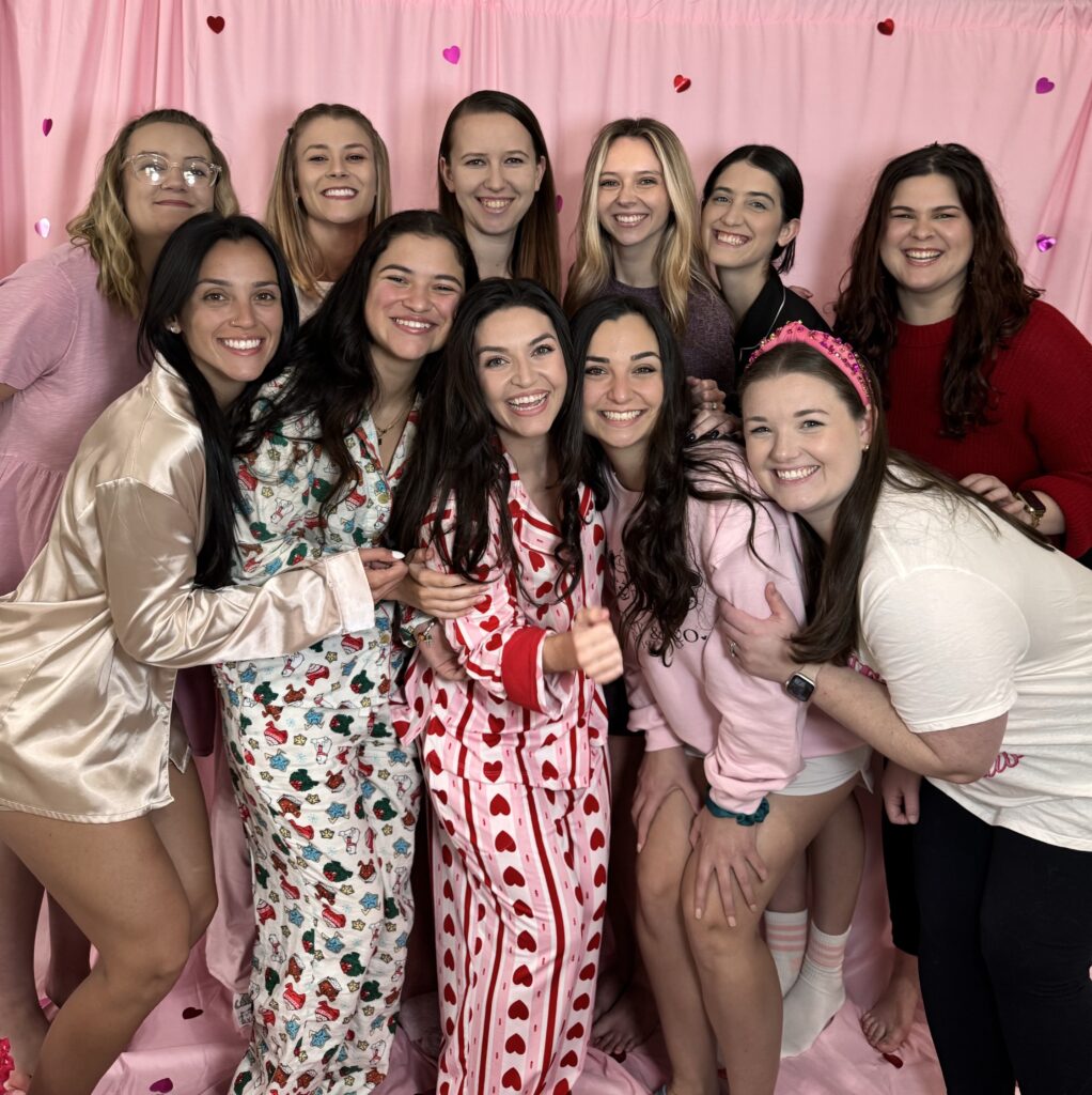 friends posing in front of a valentines themed backdrop